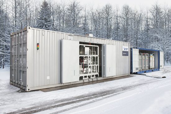 Foto de um container branco instalado no solo de um lugar coberto de neve, com árvores ao fundo totalmente secas e cobertas de neve. O container é o laboratório modular onde se produz a chamada gasolina sem petróleo.